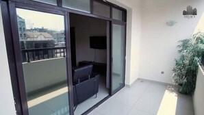 Een balkon met een schuifdeur, een flatscreen televisie en een potplant.