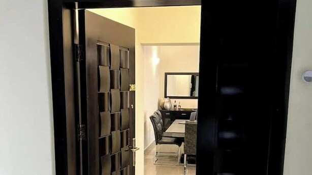 Een hotelkamer met een zwarte deur, een bed, een bureau en een stoel.