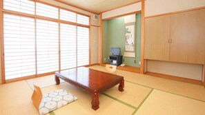 A traditional Japanese room with tatami flooring, a wooden table, a television, and a cabinet. - Ohnaru Sanso (Kami)