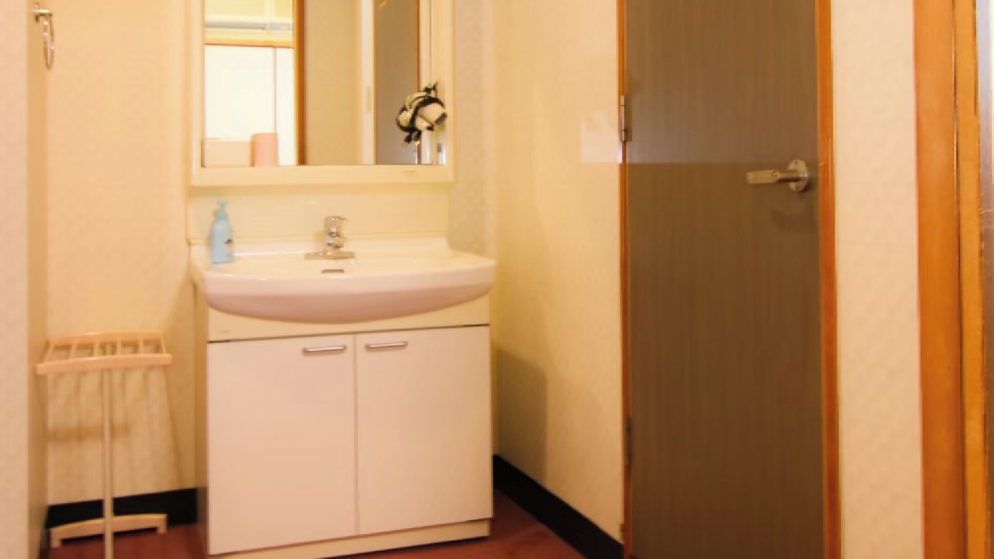 A bathroom with a white sink, mirror, and cabinet.