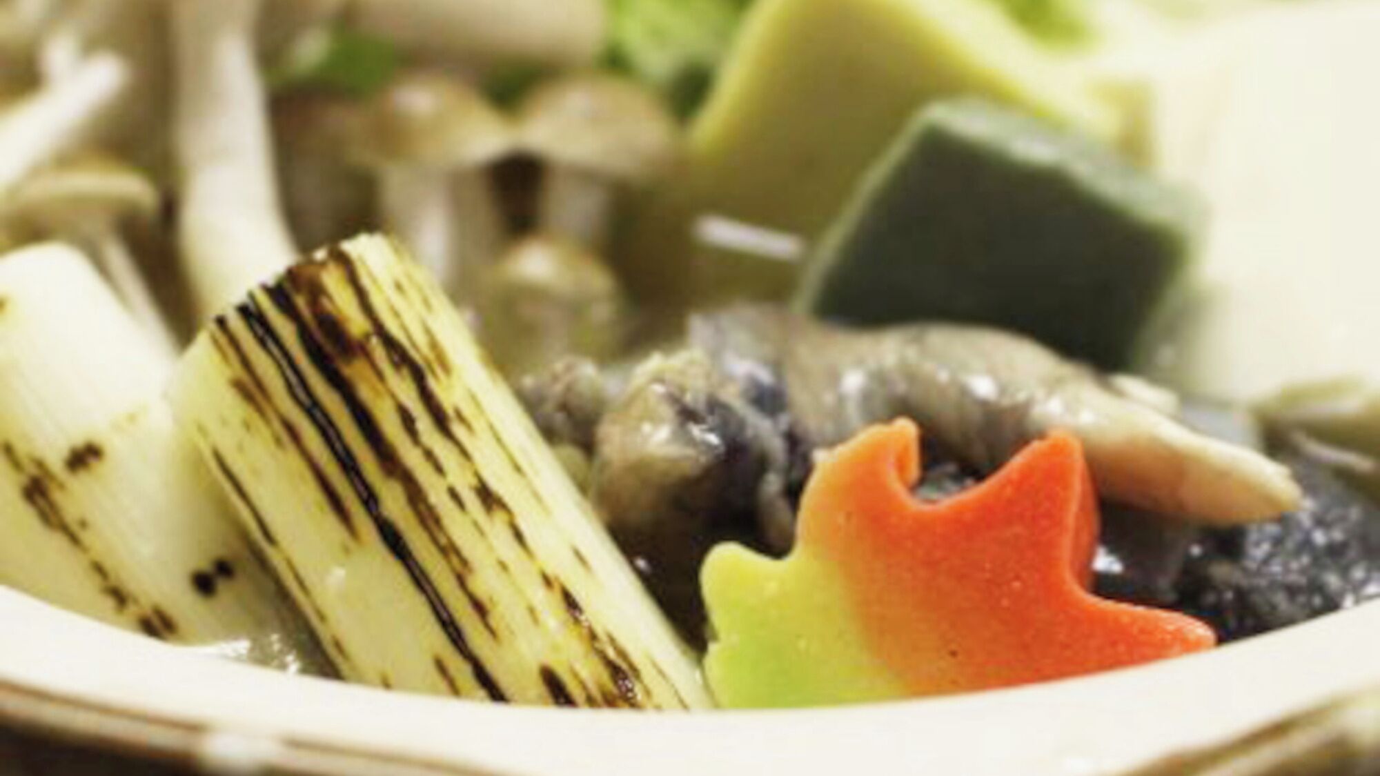 A plate with various vegetables, including a piece of grilled zucchini and a slice of carrot.