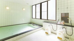 Een badkamer met een bad, een spiegel en een raam.