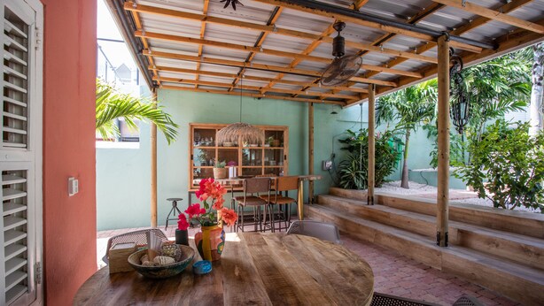 Une table en bois avec des chaises, un plafond en bois et une fenêtre donnant sur un jardin.