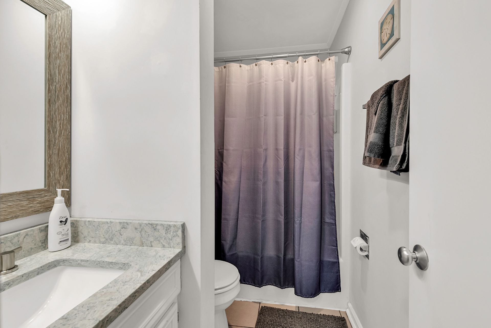 Un baño con lavamanos de mármol, inodoro, cortina de ducha y toallero.