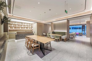 A modern hotel lobby with a central seating area, a reception desk, and a view of the outside. - Ji Hotel (Chengdu)