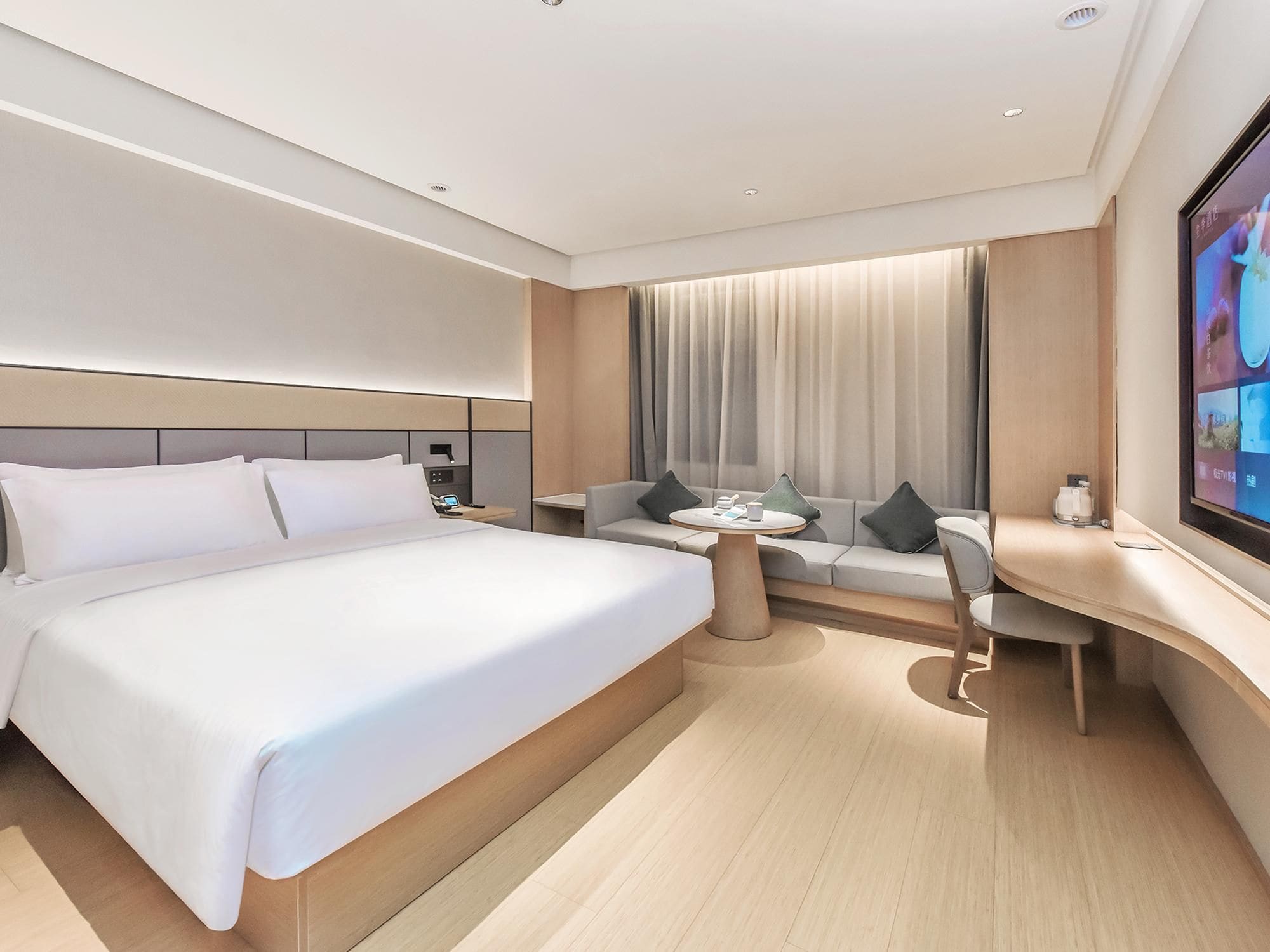 Une chambre d’hôtel moderne équipée d’un grand lit, d’un canapé, d’un bureau et d’une télévision.