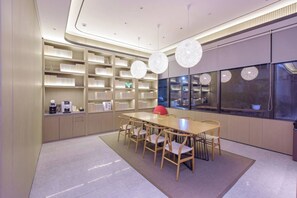 Une cuisine moderne avec un coin repas, comprenant une longue table en bois, des chaises et une bibliothèque intégrée dotée d’étagères éclairées.