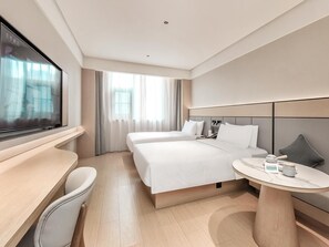 Une chambre d’hôtel avec un grand lit, un bureau, une chaise, une table ronde et une fenêtre avec des rideaux.