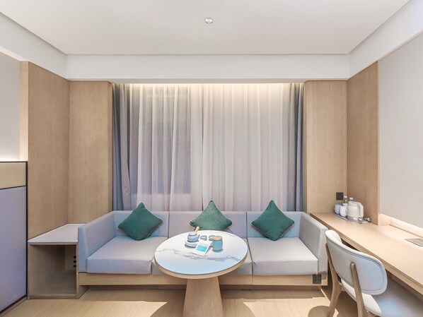 Une chambre d’hôtel moderne comprenant un canapé, une table basse ronde et un bureau avec une chaise.