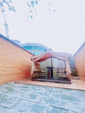 An outdoor seating area with a covered table and chairs, a tiled floor, and a wooden wall. - Ji Hotel (Chengdu)