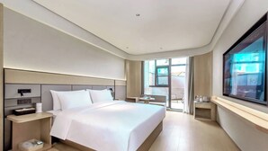 Un hotel moderno con una cama grande, mesitas de noche, un televisor y vistas al exterior.