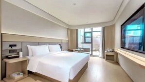 Una habitación de hotel moderna con una cama grande, mesitas de noche, un escritorio y una ventana con vistas.