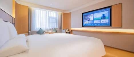 A modern hotel room with a large bed, a flat-screen TV mounted on the wall, and a small seating area with a table and chairs.