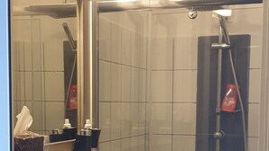 Une salle de bain avec une douche à parois de verre, un lavabo blanc et un miroir.