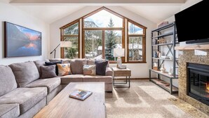 A spacious living room with a large window, a fireplace, and a cozy seating area.