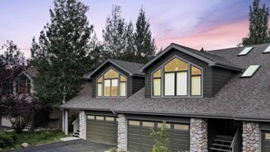 A two-story house with a stone foundation, a garage with a stone wall, and a driveway.
