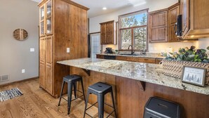 A kitchen with wooden cabinets, a granite countertop, and two stools.