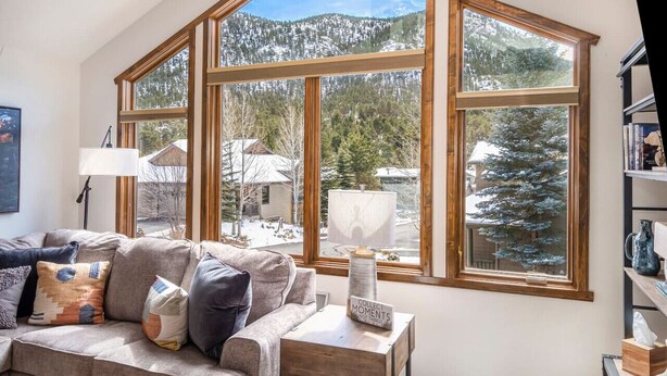 A cozy living room with a large bay window overlooking a snowy mountain landscape.