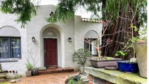 A house with a brick pathway leading to a red door, surrounded by potted plants and a tree. - Lida's House, Walk to Everything (Arcata)