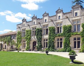 Un bâtiment historique à la façade symétrique, doté de fenêtres en arc de cercle et d’une entrée centrale.