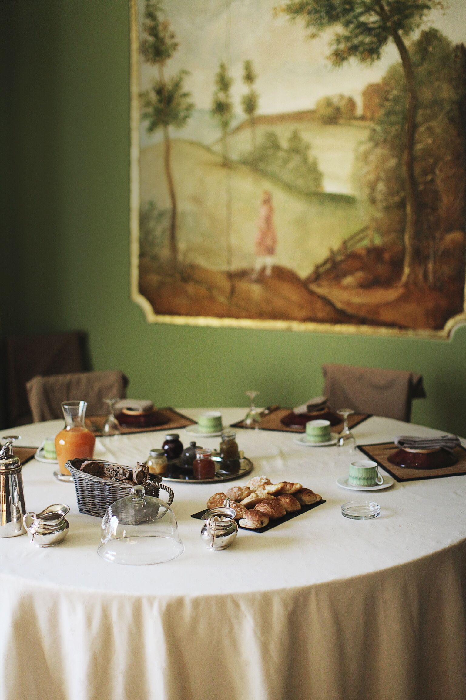 Een eettafel gedekt met verschillende gerechten, een schilderij aan de muur en een groene wand.
