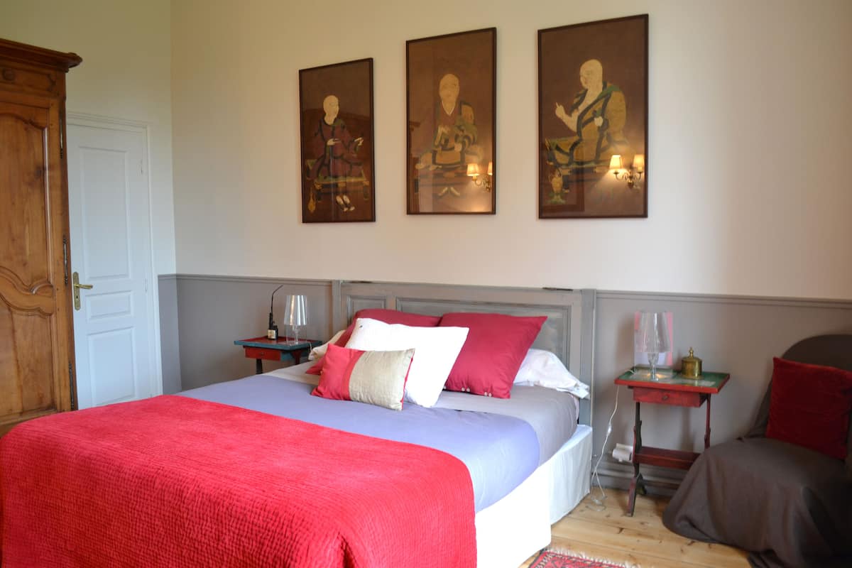 Une chambre à coucher comprenant un lit, des tables de chevet, une commode et des œuvres d’art murales.