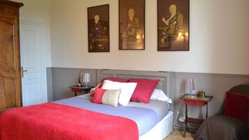 A bedroom with a bed, nightstands, a dresser, and wall art.