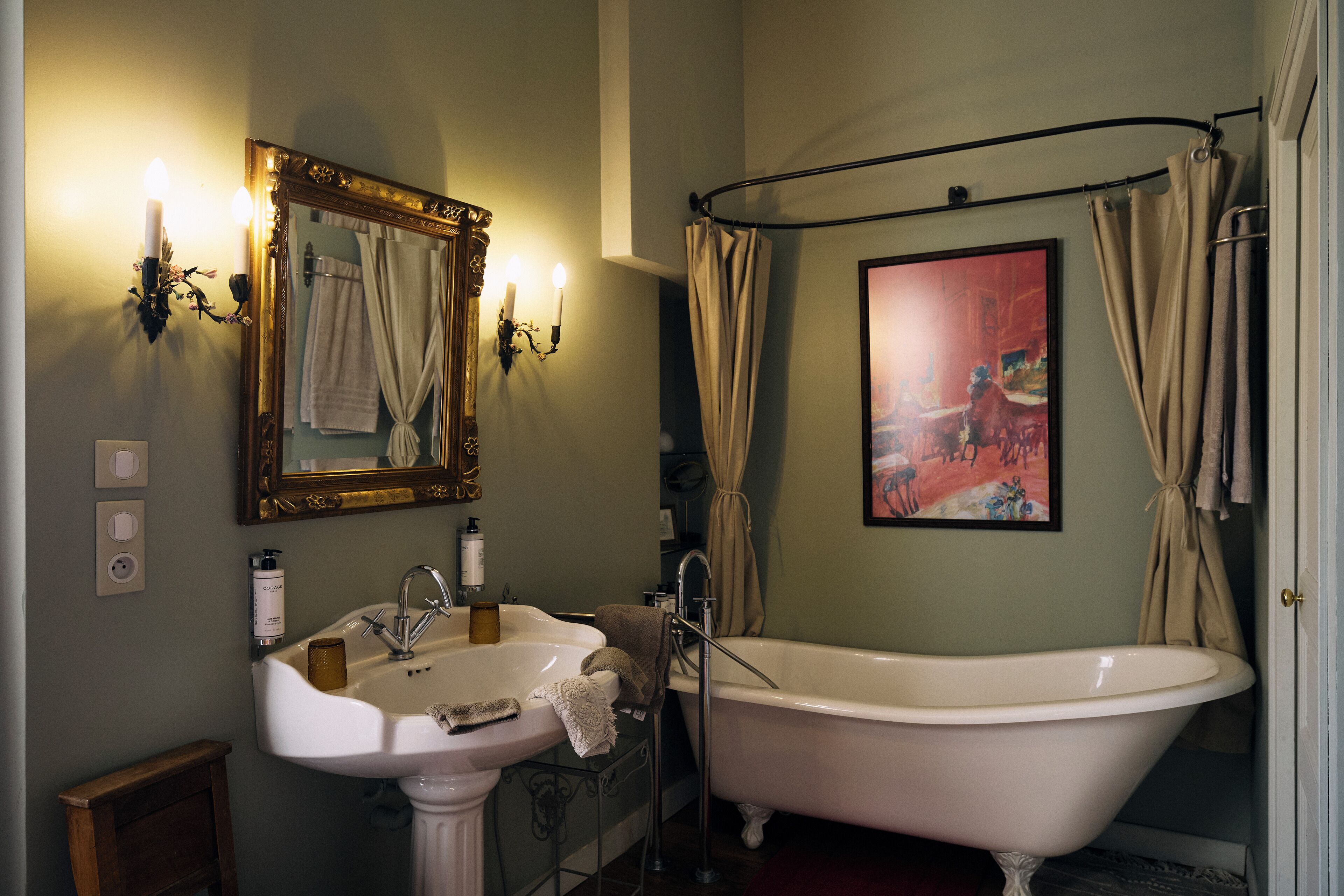 A bathroom with a white sink, a bathtub, a mirror, and a shower curtain.