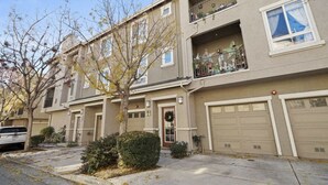 A two-story residential building with a front garage door, a small front porch, and a balcony on the second floor. - Newly Remodeled Townhouse Communication Hill (San Jose)