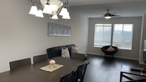 A dining area with a dark wood table, chairs, a chandelier, a ceiling fan, and a large window with blinds. - Newly Remodeled Townhouse Communication Hill (San Jose)