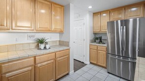 A kitchen with wooden cabinets, a stainless steel refrigerator, and a tiled backsplash. - Newly Remodeled Townhouse Communication Hill (San Jose)