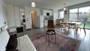 Une cuisine moderne avec des meubles blancs, un réfrigérateur et un coin repas comprenant une table et des chaises.