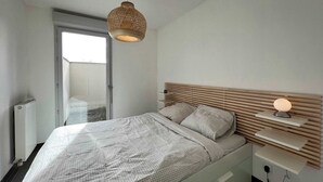 Une chambre à coucher moderne avec un lit, des tables de chevet et un luminaire suspendu.