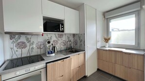 Une cuisine moderne avec des meubles blancs, un four à micro-ondes, une bouilloire et une fenêtre donnant sur un beau paysage.