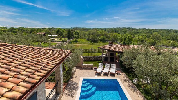 A rooftop pool with a clear view of the surrounding landscape, including a stone building and a grassy area.