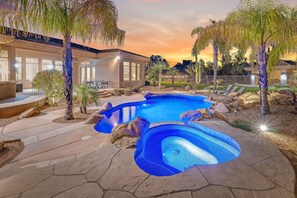 A swimming pool with a stone deck, surrounded by palm trees and a house with large windows. - Desert Oasis ★Pool-Spa-Disc Golf-Ping Pong-Poker Table-Pool Table★ (Scottsdale)