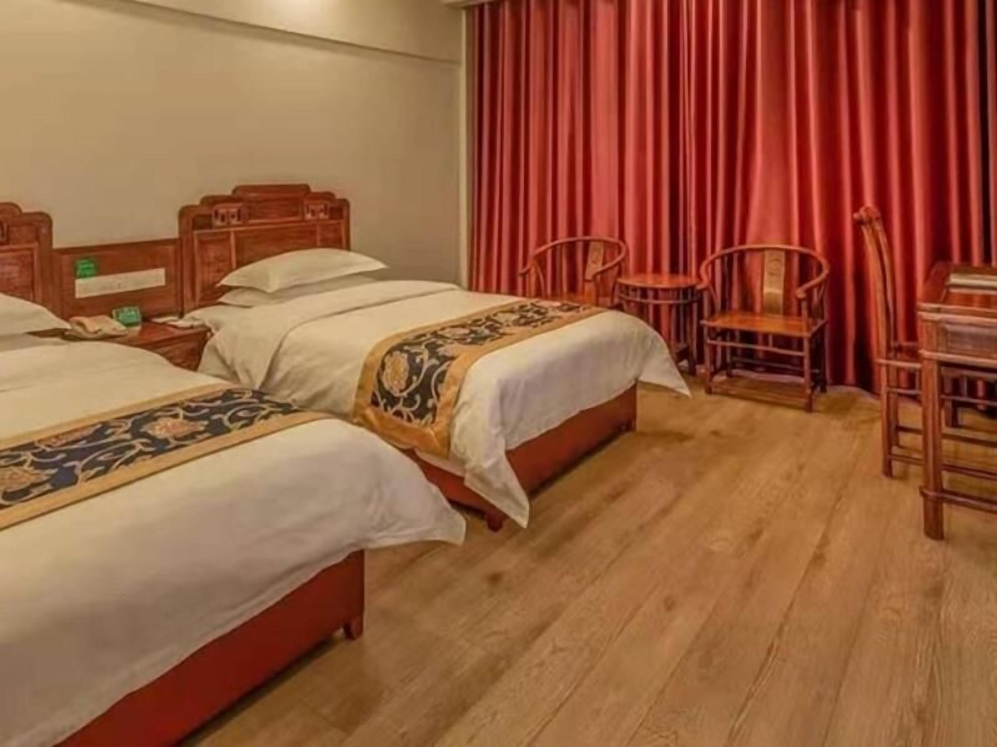 Habitación de hotel con dos camas, cabeceros de madera, una mesita y una silla.