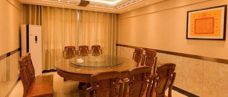 A conference room with a round table, wooden chairs, a whiteboard, and a framed picture on the wall.