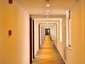 A long, narrow hotel corridor with a patterned carpet and light-colored walls.