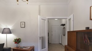 Ein Wohnzimmer mit einer Couch, einem Couchtisch, einer Lampe, einer Vase mit Blumen und einem Bücherregal.