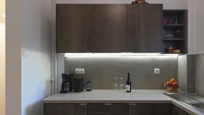 Eine moderne Küche mit dunklen Holzausführungen, einer integrierten Kaffeemaschine, einer Weinflasche und einer Obstschale.