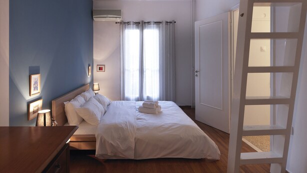 Ein Schlafzimmer mit einem Bett, Nachttischen, einer Lampe und einem Fenster mit Vorhängen.
