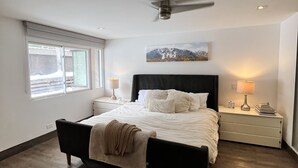 A bedroom with a bed, a ceiling fan, a nightstand with a lamp, and a window with blinds. - monarch chalet aspen condo (Aspen)