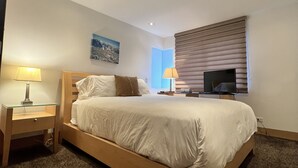 A hotel room with a single bed, bedside tables, a TV, and a painting on the wall. - monarch chalet aspen condo (Aspen)