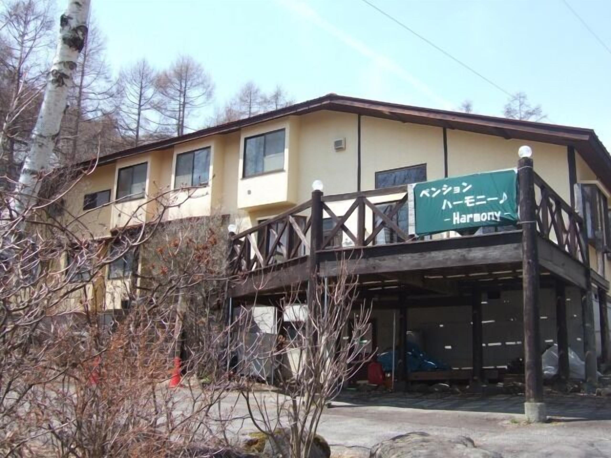 A building with a balcony, a sign with Japanese text, and a clear sky.