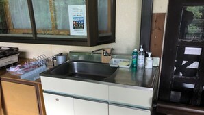 Una cocina con un lavamanos de acero inoxidable, una ventana con un cartel y una puerta de madera.