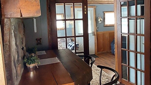 A rustic cabin interior with a wooden dining table, chairs, and a bench. - Tiny Cabin in Huron National Forest! (Luzerne)