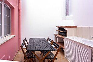 A compact kitchen with a wooden table and chairs, a built-in oven, and a window with a screen. - Modern family home  (Faro)