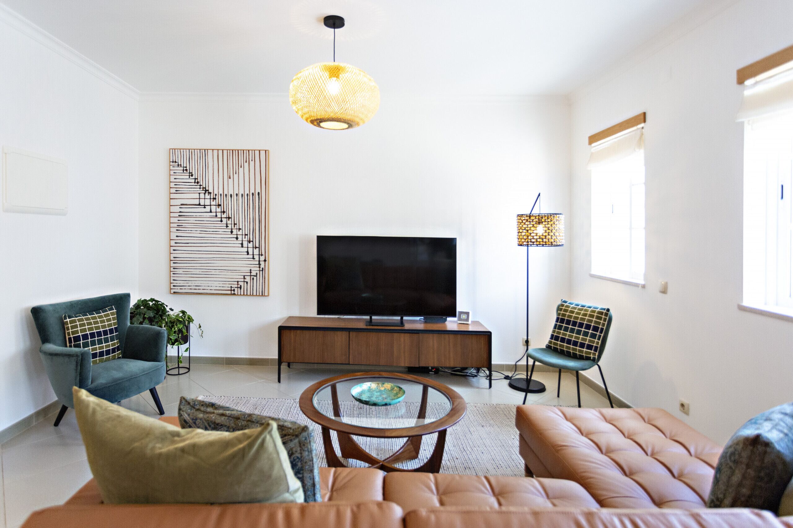 A modern living room with a sofa, armchairs, a coffee table, a TV, and decorative items.