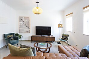 Un salon moderne comprenant un canapé, des fauteuils, une table basse, un téléviseur et des objets décoratifs.